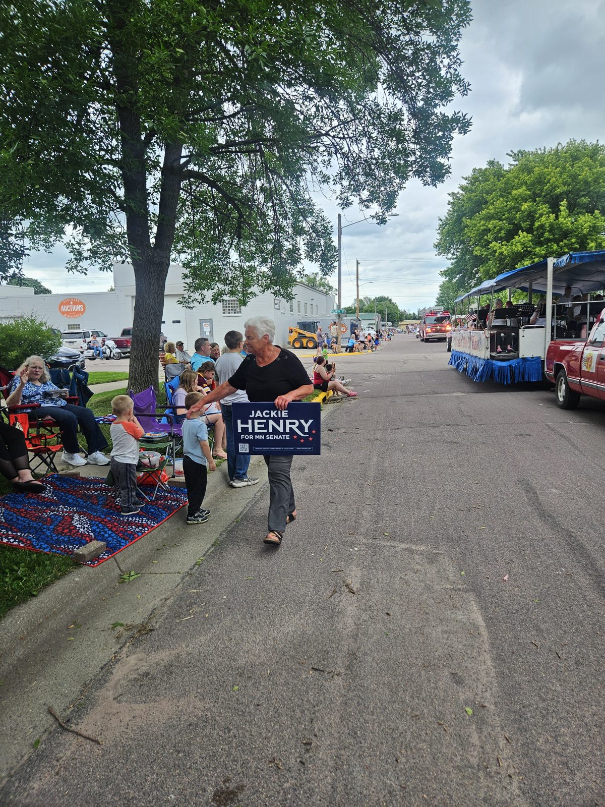 Jackie Henry walking the Nicollet parade route carrying her campaign sign